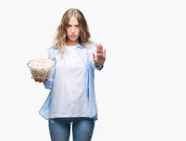 Açık eliyle dur işareti ile ciddi ve kendine güvenen ifade, savunma jest yapıyor izole arka plan üzerinde patlamış mısır yemek güzel sarışın genç kadın