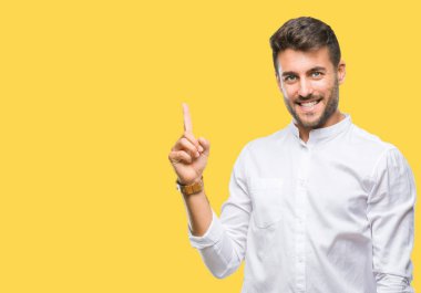 Kameraya bakarak yan el ve parmak ile işaret eden genç yakışıklı adam yüzünde kocaman bir gülümseme ile izole arka plan üzerinde.