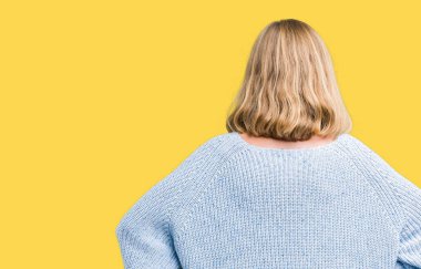 İzole arka plan ayakta geriye doğru uzakta silah ile vücut üzerinde seyir üzerinde mavi kazak giyen güzel genç kadın