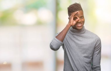 Genç Afro-Amerikan adam gülümsüyor, parmakları ile mutlu yüz üzerinden seyir göz el ile ok jest yapıyor izole arka plan üzerinde.