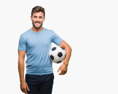 Futbol futbol topu ayakta ve diş gösterilen kendine güvenen bir gülümsemeyle gülümseyerek mutlu bir yüz ile izole arka plan üzerinde tutan genç yakışıklı adam