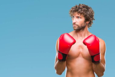 Yakışıklı İspanyol boksör adam boks eldivenli görünümlü yan ve dik dik bakma uzağa düşünce gülümseyen izole arka plan üzerinde.