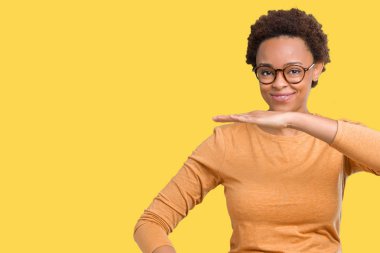 Büyük ve büyük boy işaret, ölçü birimi sembol gösteren ellerle eller izole arka plan üzerinde gözlük takan genç güzel Afrikalı-Amerikalı kadın. Kameraya bakarak gülümsüyordu. Ölçüm kavramı.