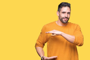 Yakışıklı delikanlı ile büyük ve büyük boy işaret, ölçü birimi sembol gösteren el eller izole arka plan üzerinde. Kameraya bakarak gülümsüyordu. Ölçüm kavramı.