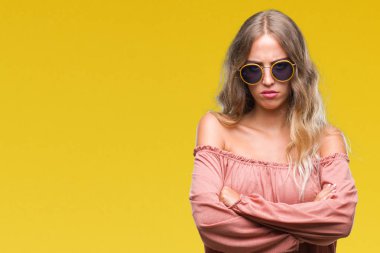 İzole arka plan şüpheci ve sinir, onaylamayan ifade yüz çapraz kolları olan Retro güneş gözlüğü takıyor güzel sarışın genç kadın. Negatif kişi.