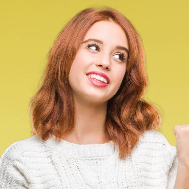 İzole arka planı arıyorum ve başparmak yanında yukarıyı mutlu yüz ile gülümseyen kış kazak giyen genç güzel kadın.