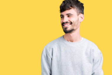 Uzak tarafına yüzünde, doğal ifade gülümseme ile seyir izole arka plan üzerinde sweatshirt giyen genç yakışıklı adam. Kendine güvenen gülüyor.