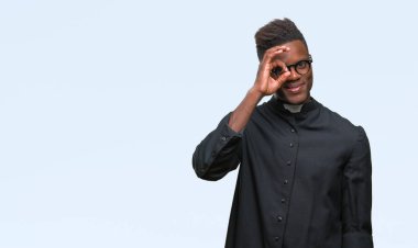 Genç Afro-Amerikan rahip adam gülümsüyor, parmakları ile mutlu yüz üzerinden seyir göz el ile ok jest yapıyor izole arka plan.