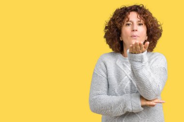 Bir öpücük el ile güzel ve seksi olmak hava üfleme kamera bakarak izole arka plan üzerinde kış kazak giyen güzel orta ager üst düzey kadın. Aşk ifade.