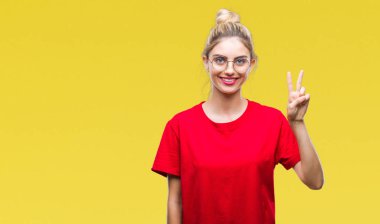 Gösterilen ve parmakları ile işaret izole arka plan üzerinde kırmızı t-shirt ve gözlük giyen genç güzel sarışın kadın ikincisi ise kendinden emin ve mutlu gülümseyerek.