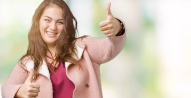 Artı boyutu genç kadın güzel izole arka plan onaylama üzerinde giyen kış ceket el ile pozitif jest yapıyor gülümseyen ve başarı için mutlu yaşasın. Kamera, kazanan jest arıyorsunuz.