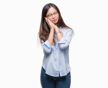 Uyku yorgun hayal ve ellerle birlikte poz ile kapalı gözler gülümseyen izole arka plan üzerinde gözlük takan genç Asya iş kadını.