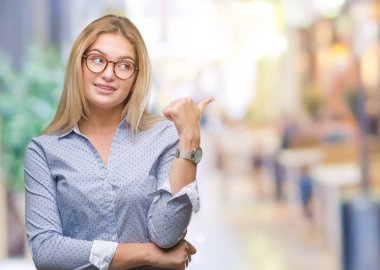 Seyir ve başparmak yanında yukarıyı mutlu yüz ile gülümseyen izole arka plan üzerinde gözlük takan Genç beyaz iş kadını.