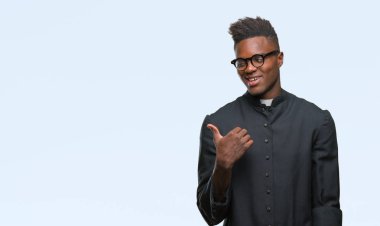 Genç Afro-Amerikan rahip adam arıyor ve başparmak yanında yukarıyı mutlu yüz ile gülümseyen izole arka plan.