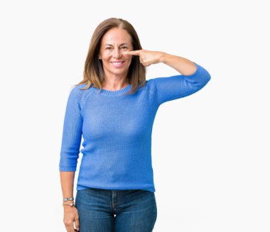 Orta yaş üzerinde kış kazak giyen güzel kadın izole arka plan yüz ve burun, neşeli gülümseyerek el parmak ile işaret