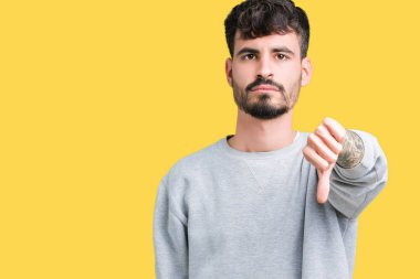 Mutsuz ve kızgın ret gösterilen ve başparmak aşağı hareketi ile negatif seyir izole arka plan üzerinde sweatshirt giyen genç yakışıklı adam. Kötü ifade.