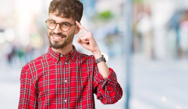 Genç yakışıklı adam gözlük izole üzerinde bir parmak, harika bir fikir ya da düşünce, iyi hafıza ile baş gösteren gülen arka plan