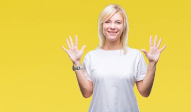Gösterilen ve parmakları ile işaret izole arka plan üzerinde beyaz t-shirt giyen genç güzel sarışın kadın kendinden emin ve mutlu gülümseyerek süre on numara.