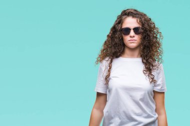 Güzel esmer kıvırcık saçlı Genç kız yüzünde ciddi bir ifade ile izole arka plan üzerinde güneş gözlüğü takıyor. Basit ve doğal kameraya bakıyor.