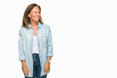 Orta yaş yetişkin kadın üzerinde rahat kot gömlek giymiş arka plan uzak tarafına gülümseme ile yüzünde, doğal ifade arıyorum izole. Kendine güvenen gülüyor.