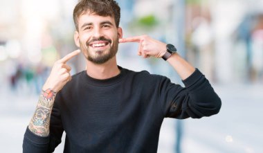 Tecrit edilmiş, güler yüzlü, kendine güvenen, parmaklarını, dişlerini ve ağzını gösteren genç yakışıklı bir adam. Sağlık kavramı.