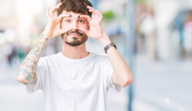 Parmaklarıyla, Uykulu ve sabah yorgunluk için yorgun gözlerini açmaya çalışırken izole arka plan üzerinde beyaz t-shirt giyen genç yakışıklı adam