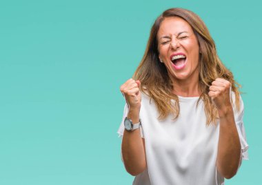 Gülümseyen ve başarı için çığlık orta yaş üst düzey İspanyol kadın izole arka plan çok mutlu ve heyecanlı kaldırdı, silah ile kazanan jest yapıyor. Kutlama kavramı.