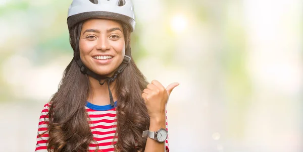 年轻的阿拉伯骑自行车妇女戴着安全头盔在孤立的背景微笑着快乐的脸看着 并指向侧面与拇指向上 — 图库照片