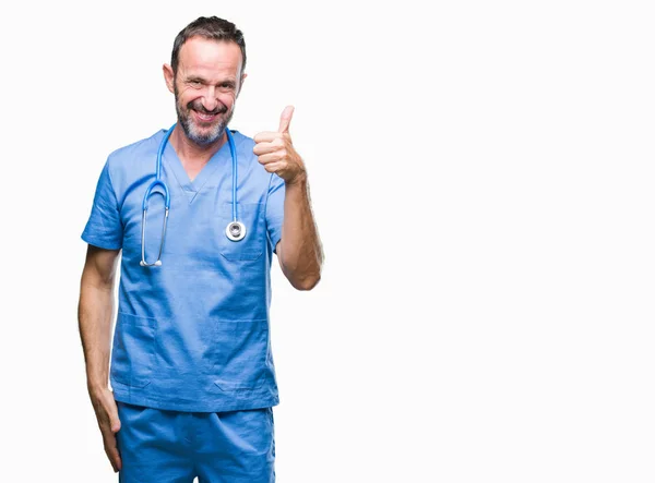 中年白发高级医生在孤立的背景下穿着医疗制服 用手做着快乐的大拇指动作 通过显示成功来批准镜头的表达 — 图库照片