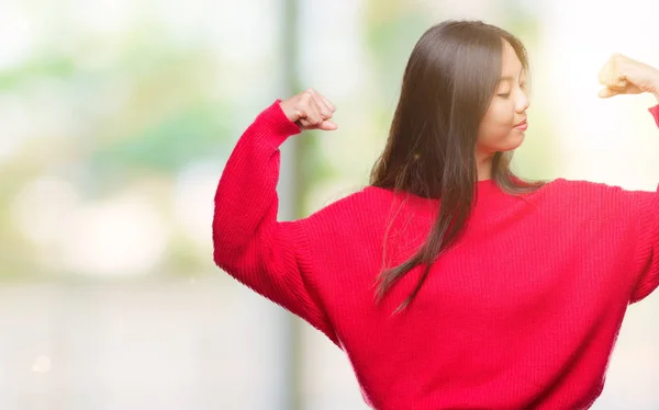 上冬のセーターを着ている若いアジア女性は 誇りに思って笑顔腕の筋肉を示す背景を分離しました フィットネスの概念 — ストック写真