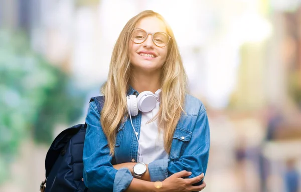 年轻美丽的金发碧眼的学生妇女戴着耳机和眼镜在孤立的背景快乐的脸微笑着交叉的手臂看着镜头 积极的人 — 图库照片