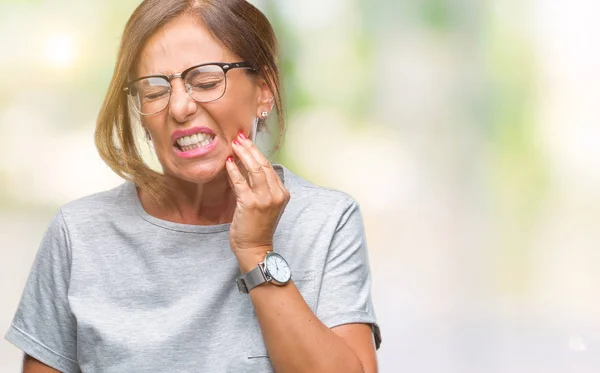 中年资深西班牙裔妇女戴着眼镜 在与世隔绝的背景下 手里带着痛苦的表情 因为牙痛或牙齿疾病 牙医概念 — 图库照片
