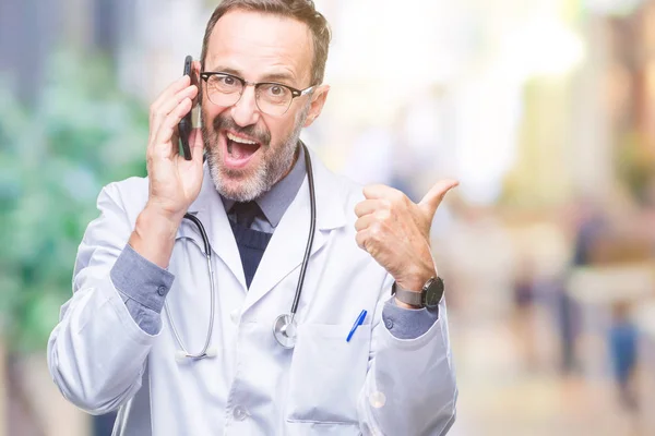 中年资深医生的人谈论智能手机在孤立的背景指向和显示与拇指到一边 快乐的脸微笑 — 图库照片
