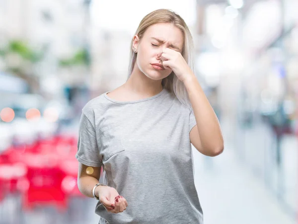 在与世隔绝的背景下 年轻的金发女郎闻到了臭味和恶心 无法忍受的气味 鼻子上握着手指的气息 坏气味概念 — 图库照片