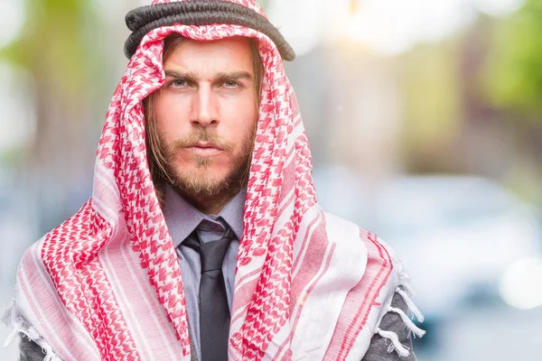 Young handsome arabian man with long hair wearing keffiyeh over isolated background skeptic and nervous, disapproving expression on face with crossed arms. Negative person.