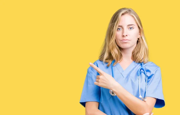 分離上医療制服を着て美しい女医女性側表示広告 深刻な穏やかな顔に手指でのポインティングを背景します — ストック写真