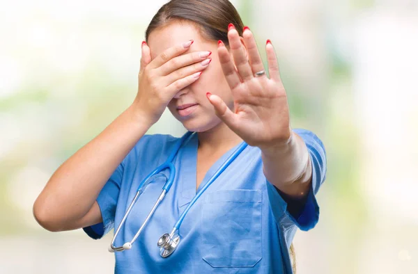 年轻的高加索医生妇女穿着医疗制服在孤立的背景覆盖眼睛用手和做停止手势与悲伤和恐惧的表情 尴尬和消极的概念 — 图库照片