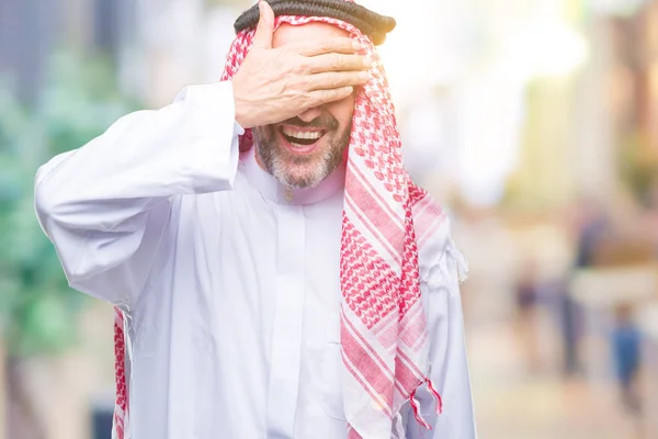 微笑し 笑う顔驚きの目を覆っている手で孤立した背景にクーフィーヤを着てシニアのアラブ人 視覚障害者の概念 — ストック写真
