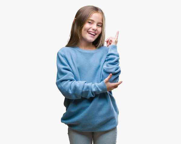 美しい少女の顔に大きな笑みを浮かべて隔離された背景に冬のセーターを着てカメラを見て側の手と指で指す — ストック写真