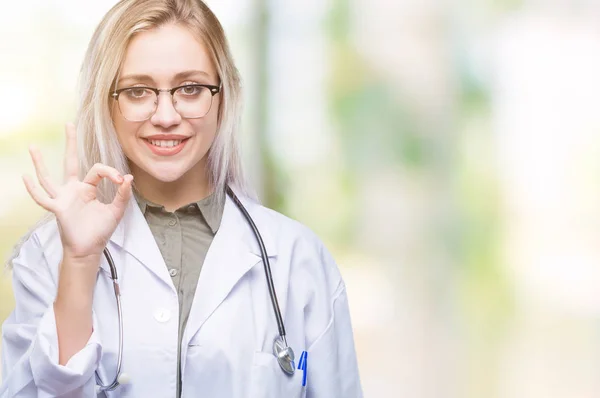 年轻的金发女医生在孤立的背景微笑积极做 标志与手和手指 成功表达式 — 图库照片