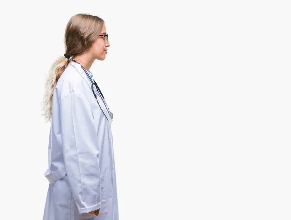 美丽的年轻金发碧眼的医生妇女穿着医疗制服在孤立的背景寻找的一面 放松的轮廓姿势与自然的脸与自信的微笑 — 图库照片