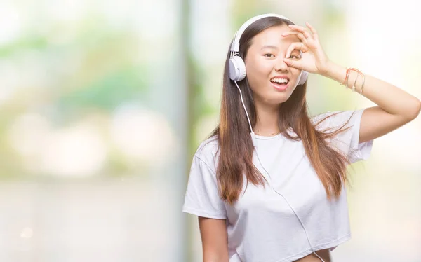 ヘッドフォンを着て音楽を聴く若いアジア女性が指を通して見る目に手で サインをして笑っている幸せそうな顔と背景を分離 — ストック写真