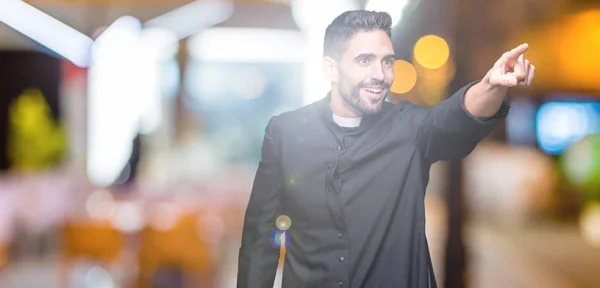 Joven Sacerdote Cristiano Sobre Fondo Aislado Señalando Con Dedo Sorprendido — Foto de Stock