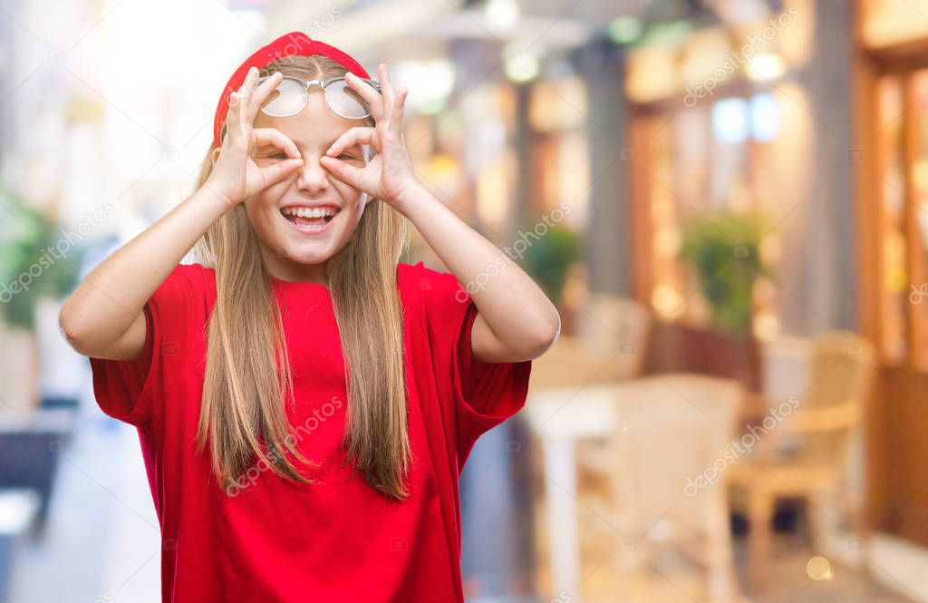 Young beautiful girl wearing glasses over isolated background doing ok gesture like binoculars sticking tongue out, eyes looking through fingers. Crazy expression.
