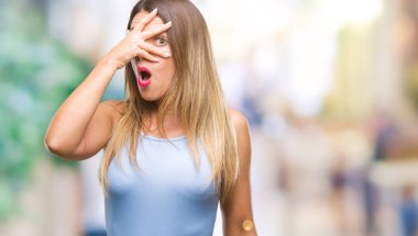 Mahcup ifadeyle parmaklarımın arasından seyir yüz ve gözler el ile kapsayan şok izole arka plan bakmak üzerinde genç güzel şık iş kadını.