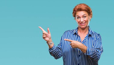 Atrractive üst düzey beyaz Kızıl saçlı kadın gülümseyerek ve iki elleri ve parmakları ile tarafına işaret kamera bakarak izole arka plan.