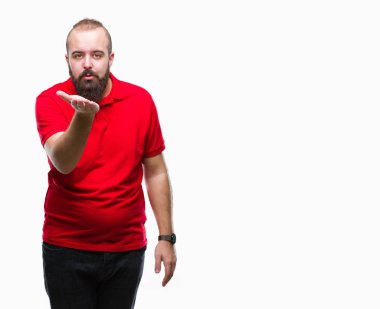 Bir öpücük el ile güzel ve seksi olmak hava üfleme kamera bakarak izole arka plan üzerinde kırmızı gömlek giymiş genç beyaz hipster adam. Aşk ifade.