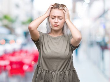 Sarışın, izole edilmiş, baş ağrısı çeken, çaresiz ve stresli genç bir kadın. Ağrı ve migren yüzünden. Ellerini başının üstüne koy..