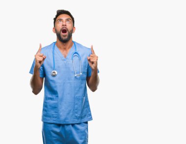 Yetişkin İspanyol doktor veya cerrah adam izole arka plan üzerinden hayran ve yukarıya bakıp parmakları ile işaret şaşırttı ve silah kaldırdı.