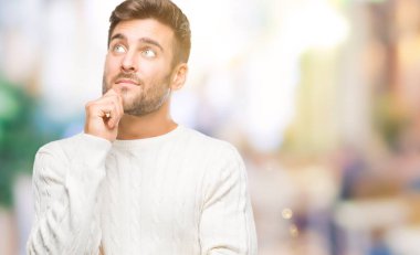 Çene düşünme hakkında soru, dalgın ifade üzerine el ile izole arka plan üzerinde kış kazak giyen genç yakışıklı adam. Düşünceli yüzüyle gülümsüyor. Şüphe kavramı.